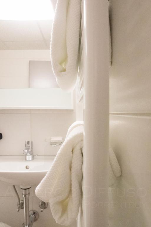 a bathroom with white towels hanging on a wall at Albergo Diffuso Porrentruy in Porrentruy