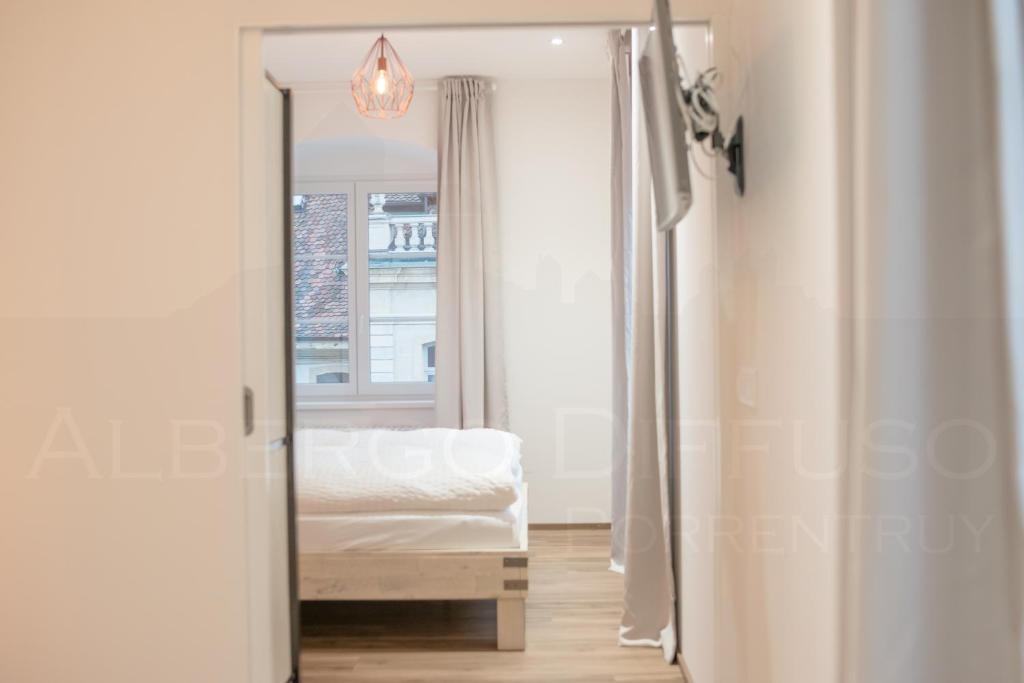 a mirror in a bedroom with a bed and a window at Albergo Diffuso Porrentruy in Porrentruy