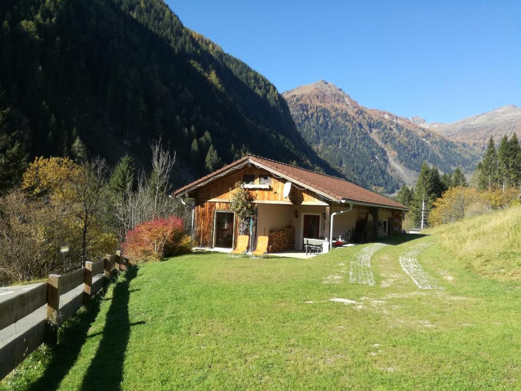 a house in a field with mountains in the background at Ferienhaus am Wallnerhof in Flattach