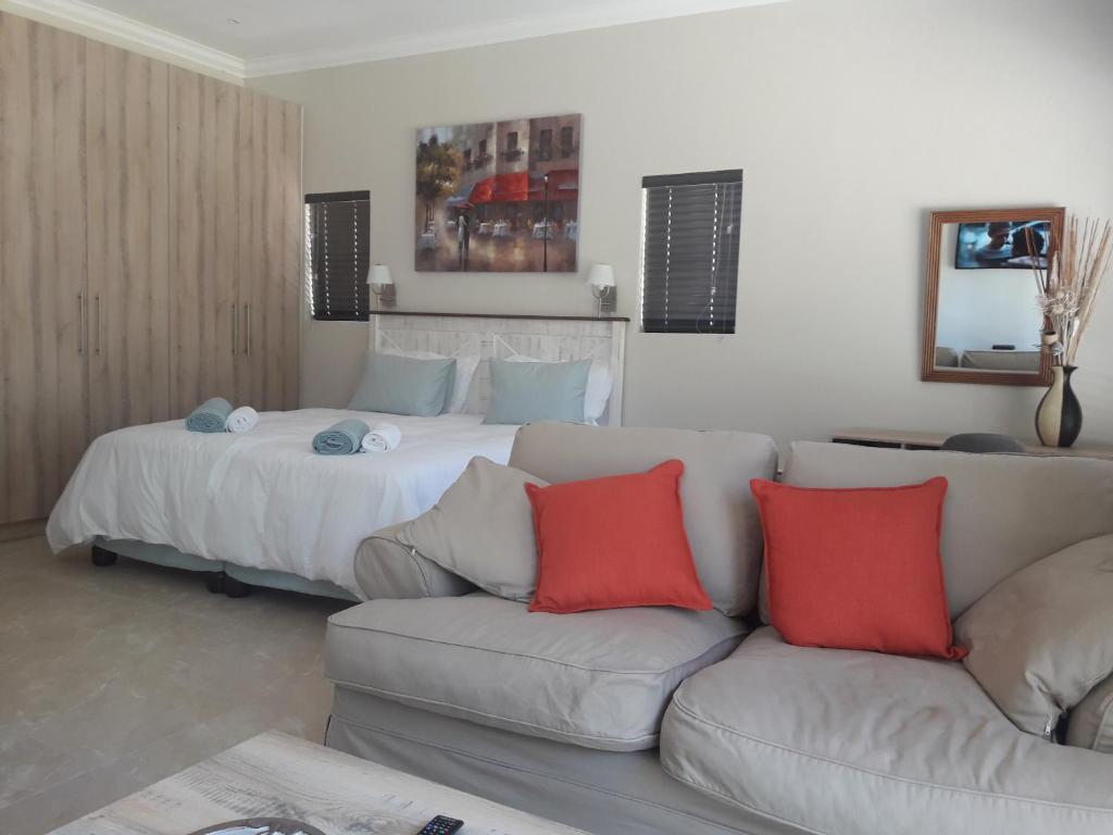 a bedroom with a bed and a couch with red pillows at Cottage@Somerset in Somerset West
