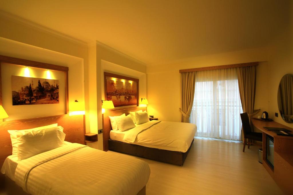 イスタンブールにあるBeyoglu MLS Hotelのベッド2台とデスクが備わるホテルルームです。