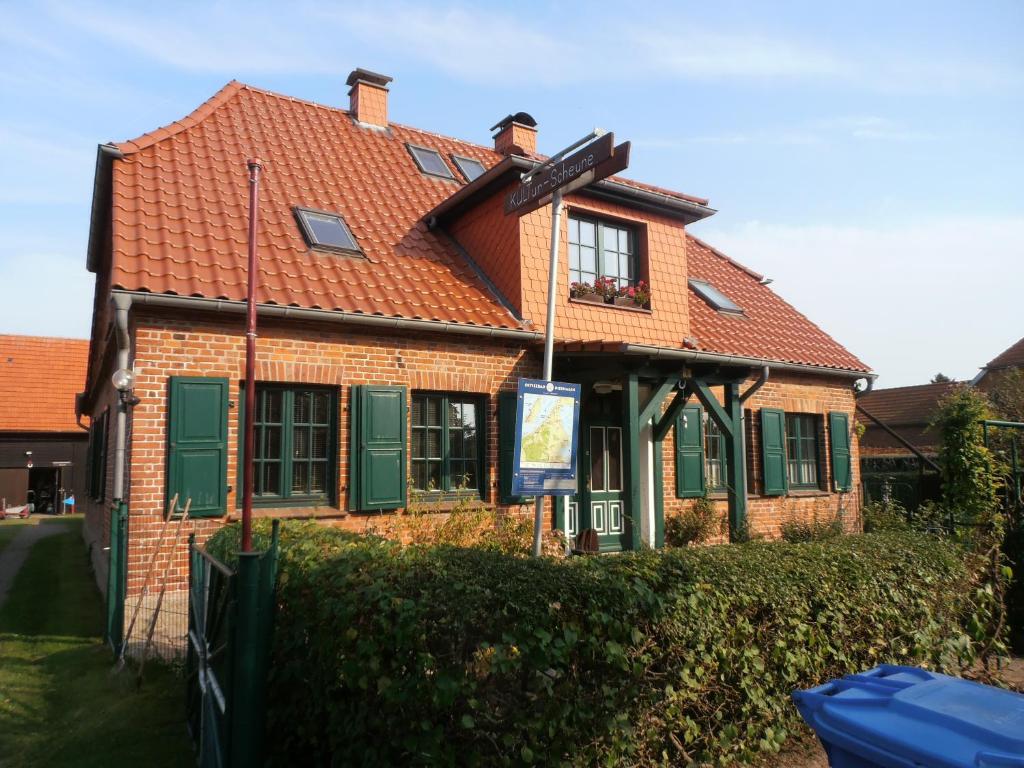 a brick house with a red roof and green shutters at Büdnerei 51 in Dändorf