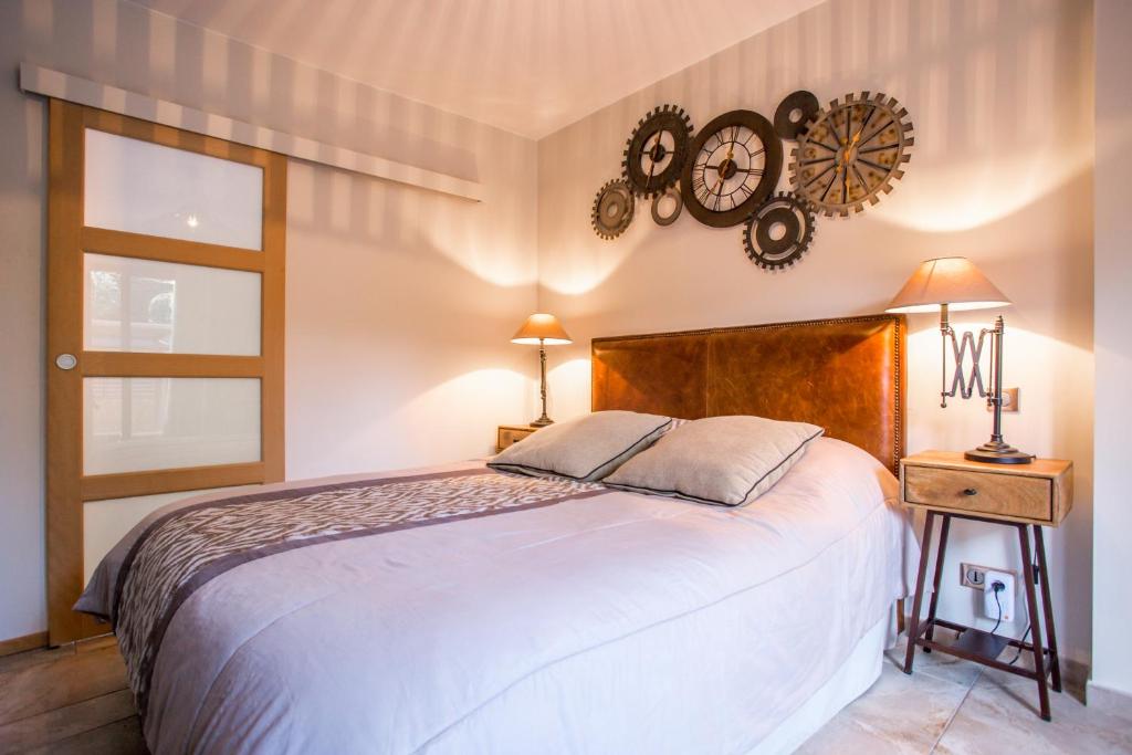 1 dormitorio con 1 cama y reloj en la pared en Domaine Les Cigales, en Mouans-Sartoux