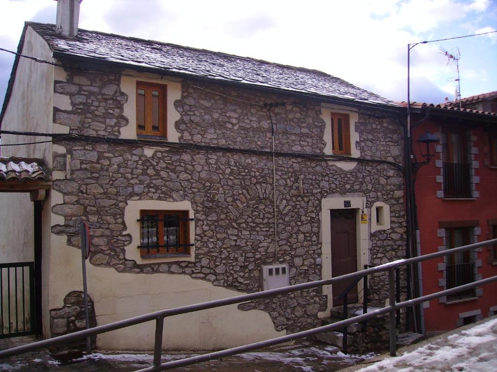 una antigua casa de piedra con una puerta y una escalera en Cal Duran, en Bellver de Cerdanya 