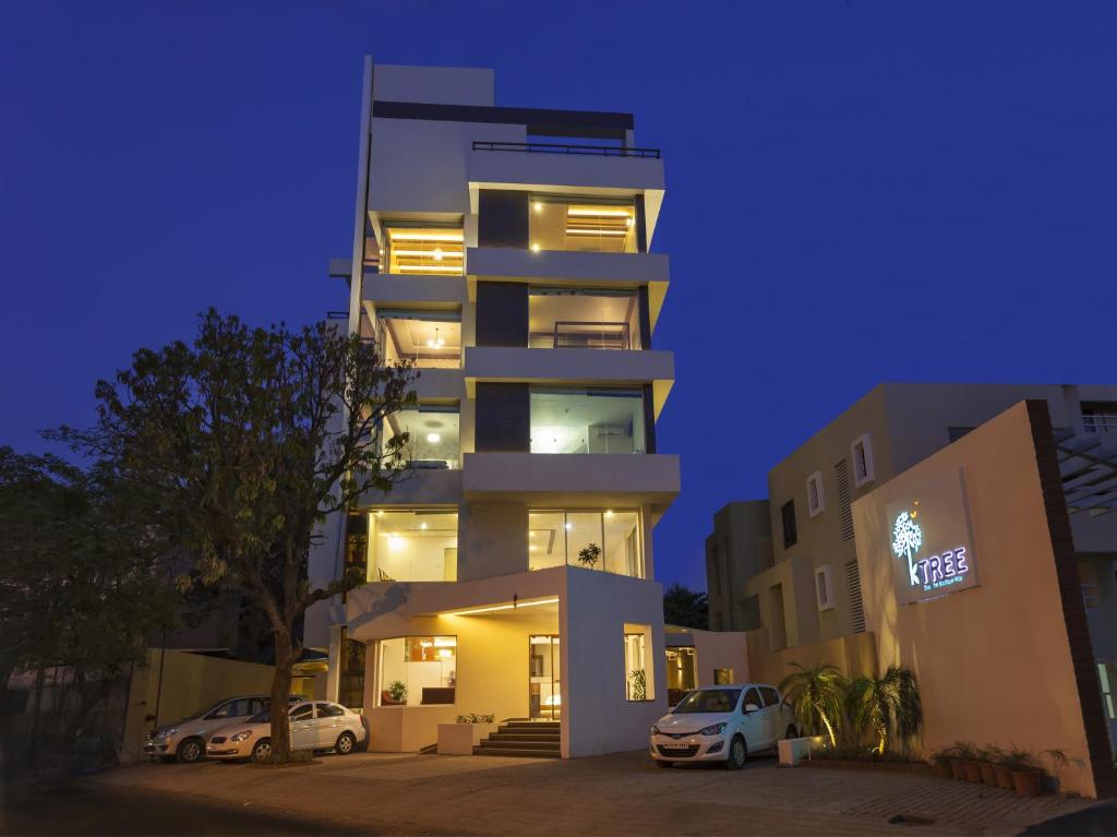 un edificio alto con due auto parcheggiate di fronte di Hotel K Tree - A Boutique Hotel a Kolhapur