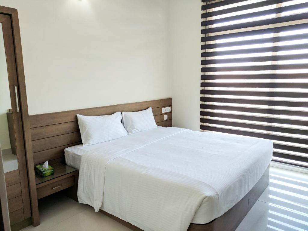 a bedroom with a white bed and a window at Clyford Suites in Bengaluru