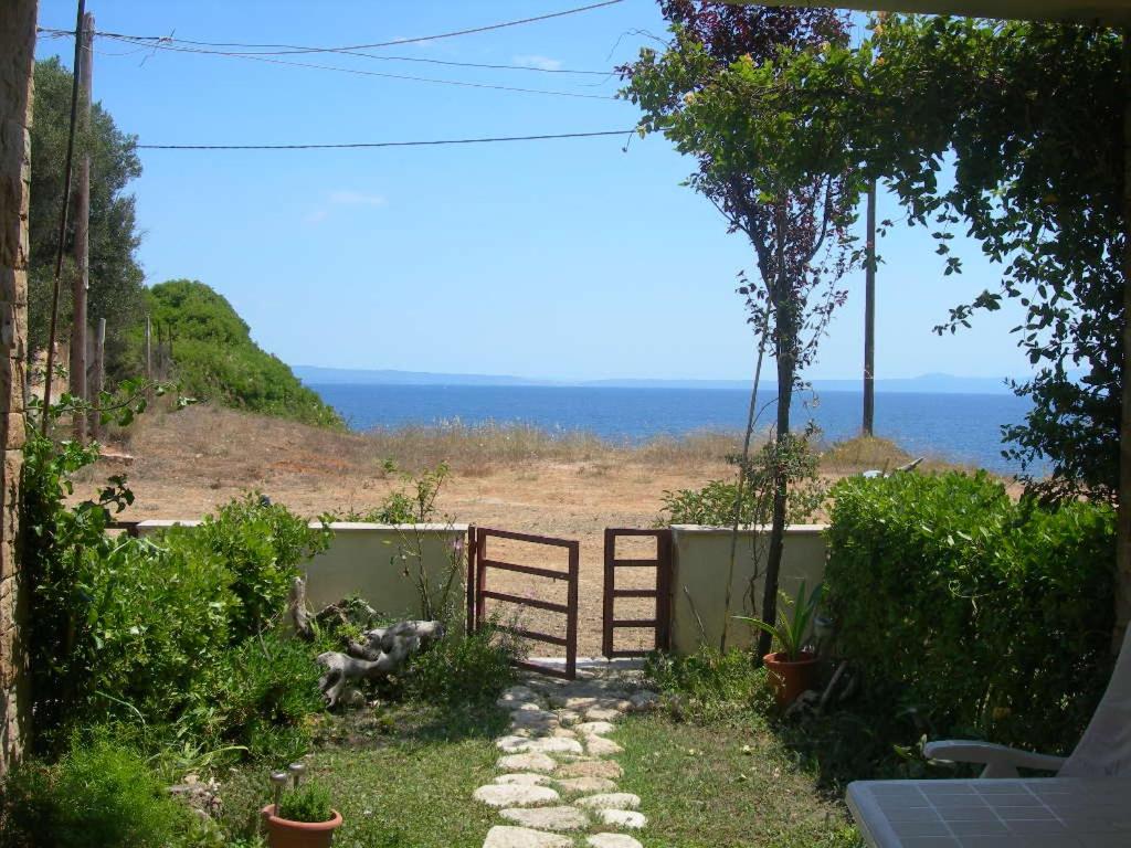 a garden with a gate and a view of the ocean at House in Front of the Sea in Nea Fokea