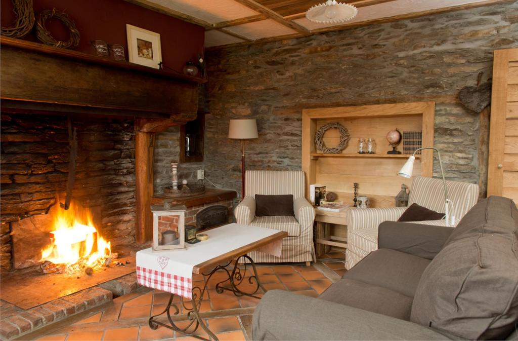 a living room with a fireplace and a stone wall at Le Saint Urbain in Nollevaux