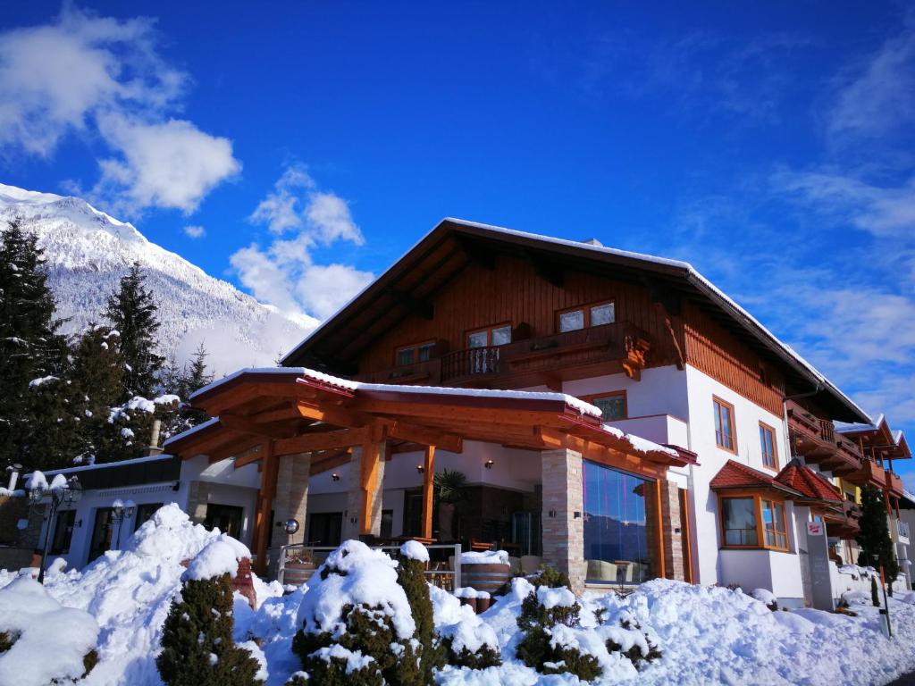 a house in the snow with a mountain at Hotel Kärntnerhof & SeeBlick Suiten in Presseggersee