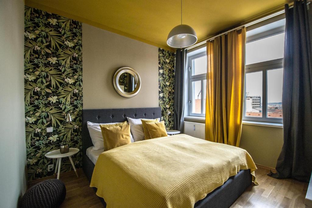 a bedroom with a bed with yellow sheets and a window at Stylish Apartments close to Eden Garden in Prague