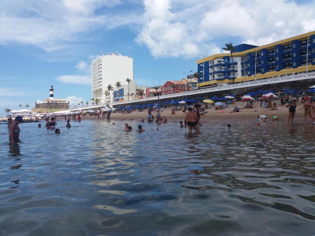 a group of people in the water on a beach at Apart-Hotel na Praia do Farol da Barra in Salvador