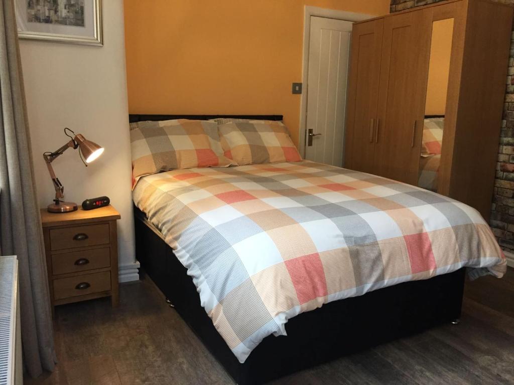 a bedroom with a bed and a lamp on a night stand at Cosy Apartment in Private Courtyard in Preston