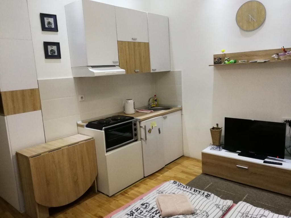 a small kitchen with white cabinets and a television at Imperia Apartments in Belgrade