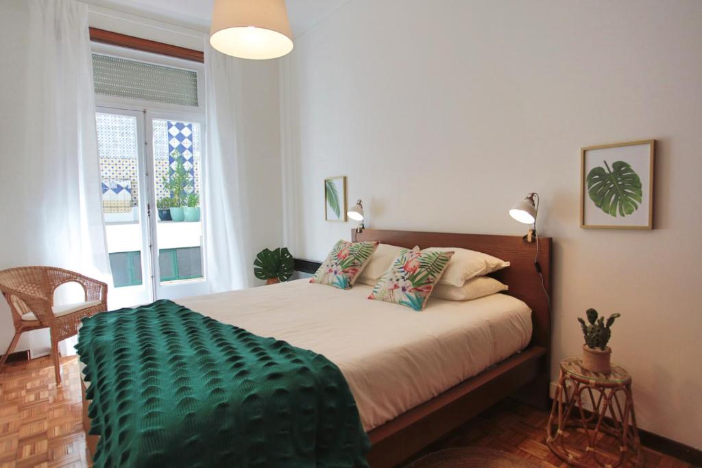 Un dormitorio con una cama con una manta verde. en Virtudes Patio en Oporto