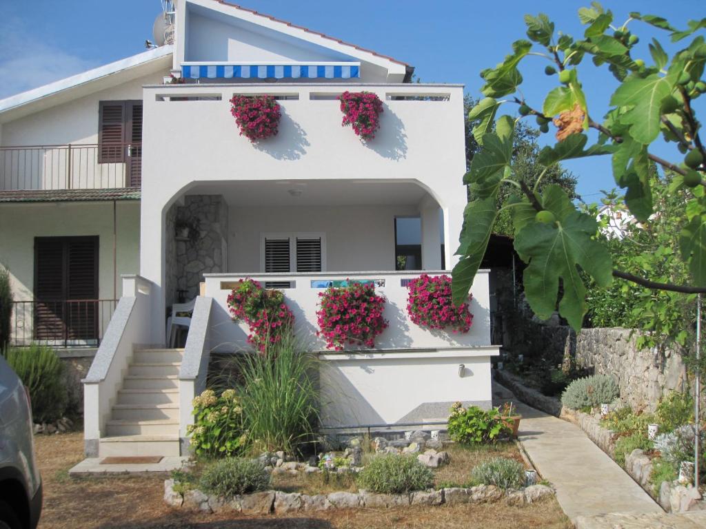 une maison blanche avec des fleurs sur son côté dans l'établissement Vila Kraljica, à Malinska