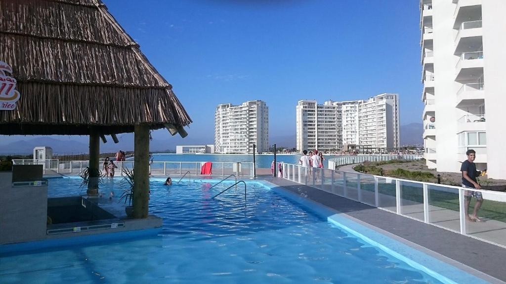 a swimming pool with people in the water and buildings at Departamento La Serena Laguna del Mar in La Serena