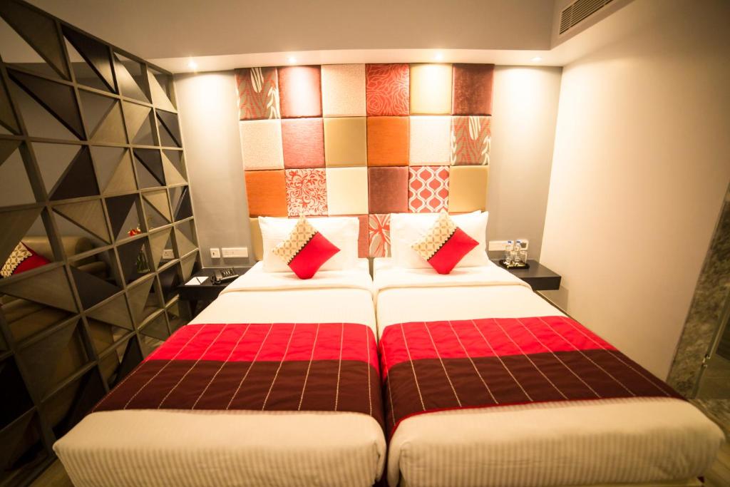 a bedroom with two beds with red pillows at Regency Tirunelveli By GRT Hotels in Tirunelveli