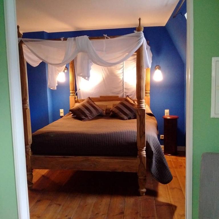 a bedroom with a canopy bed with a blue wall at Strumpfeck Suites in Traben-Trarbach