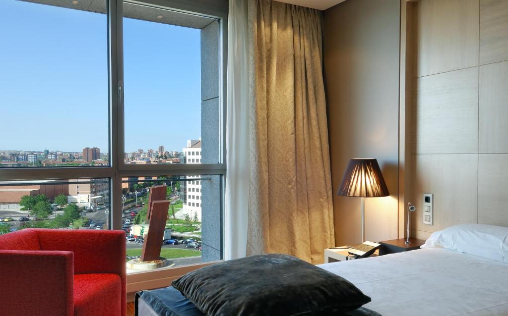 バリャドリッドにあるVincci Frontauraのベッドと大きな窓が備わるホテルルームです。