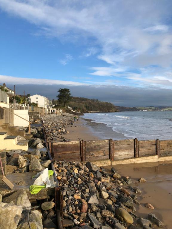 a fence on a rocky beach with the water at Wogan Cottage in Saundersfoot