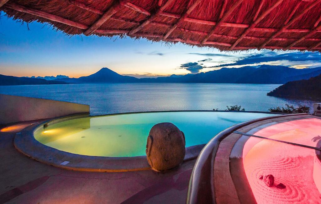 uma banheira de hidromassagem com vista para a água e as montanhas em Tzampoc Resort em Santa Catarina Palopó