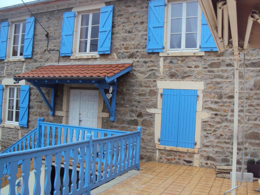 een huis met blauwe ramen en een blauwe deur bij Maison LES BLEUETS in Le Perréon