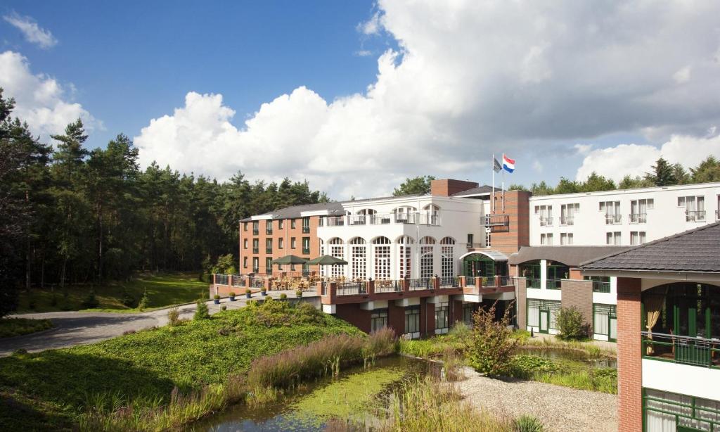 ein Hotel mit einem Fluss vor den Gebäuden in der Unterkunft Bilderberg Résidence Groot Heideborgh in Garderen