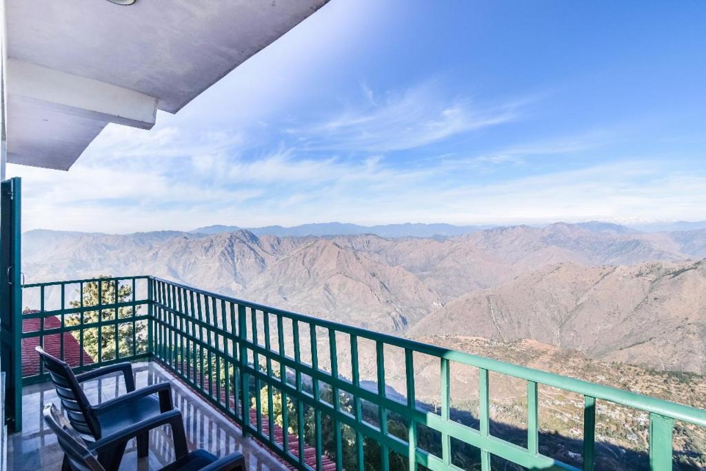 a balcony with two chairs and a view of the mountains at Trimurti Pine Valley Resort in Shimla
