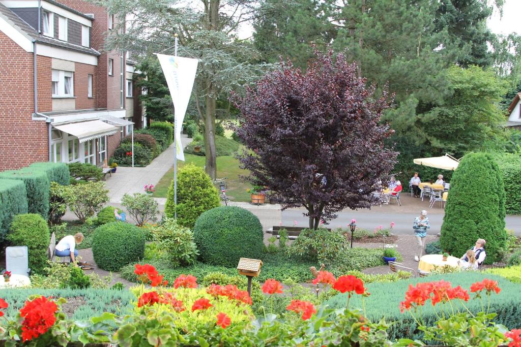 un jardín con flores y gente sentada en las mesas en Hotel-Pension Haus Holtdirk, en Lippstadt