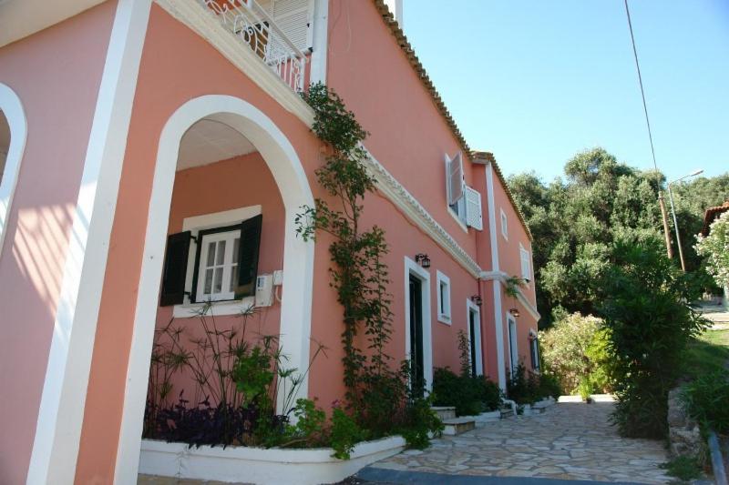 a pink building with an arch next to a street at Stavroula Studios in Paleokastritsa