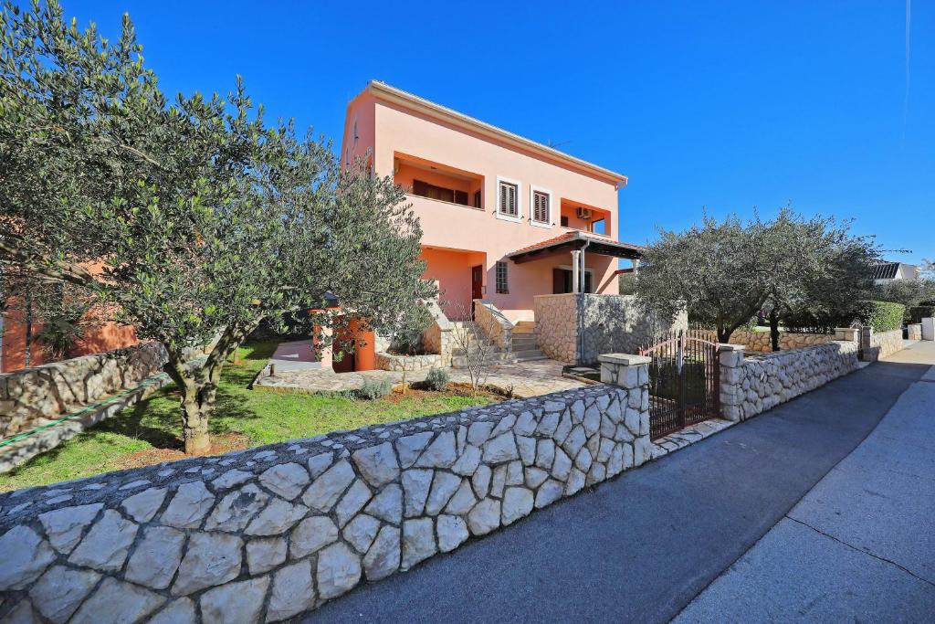 a house with a stone retaining wall and trees at Apartment Lucy in Kožino