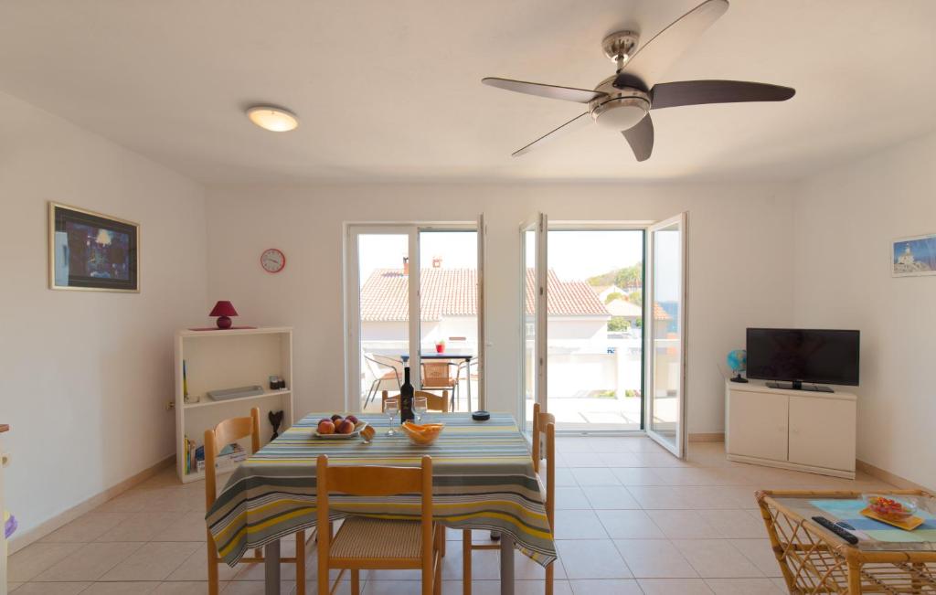 een eetkamer met een tafel met stoelen en een plafondventilator bij Sali Modern Seaview Apartment in Sali