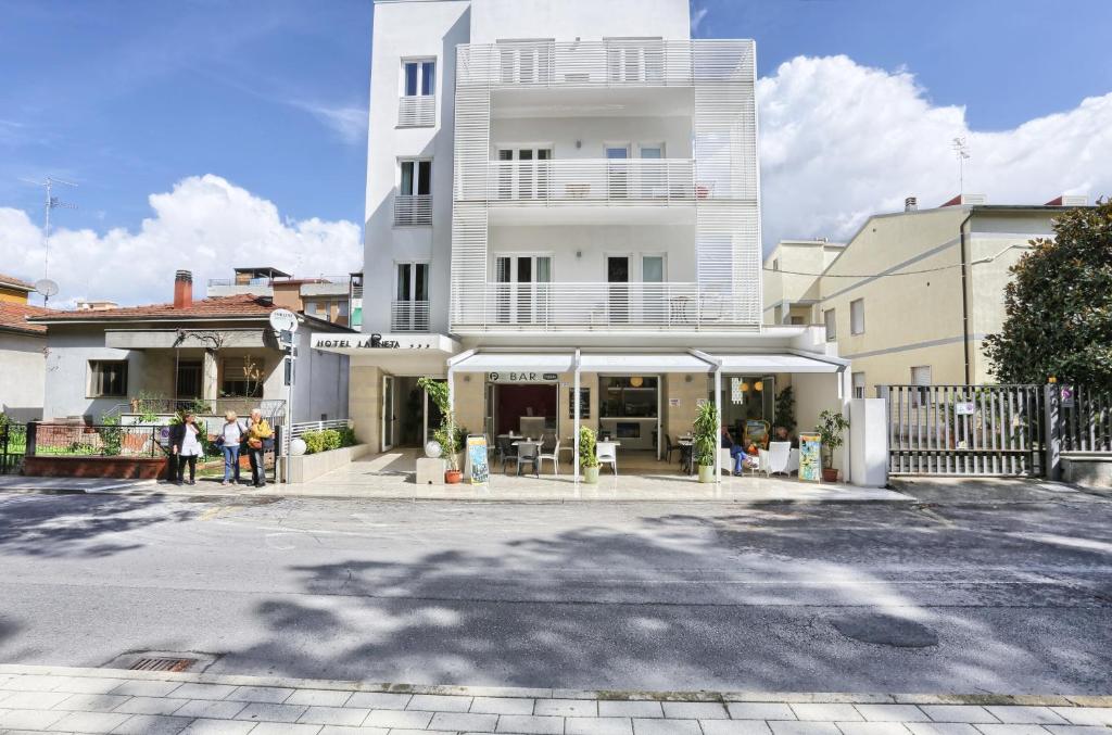 Un bâtiment blanc avec des personnes debout devant lui dans l'établissement Hotel La Pineta, à Follonica