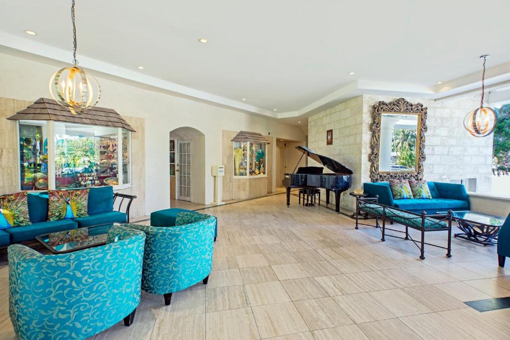 a living room with blue couches and a piano at Bougainvillea Barbados in Christ Church