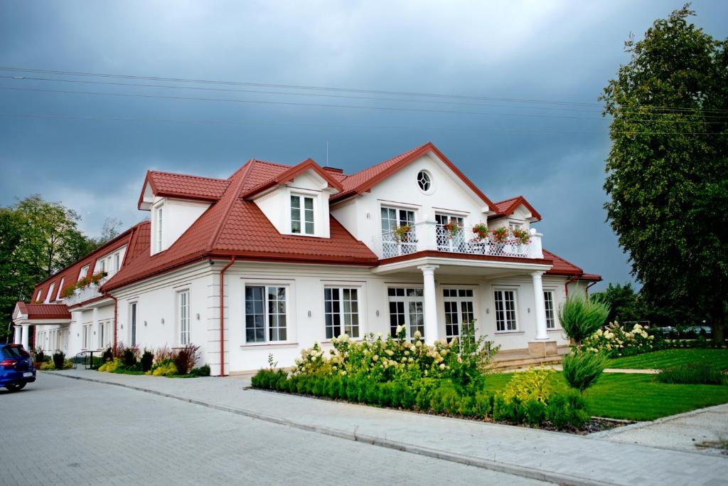 une maison blanche avec un toit rouge dans l'établissement Miód Lawenda, à Biardy