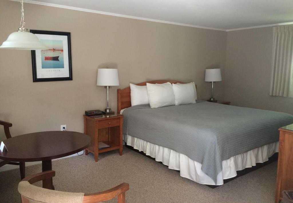 a hotel room with a bed and a table at The Chatham Motel in Chatham