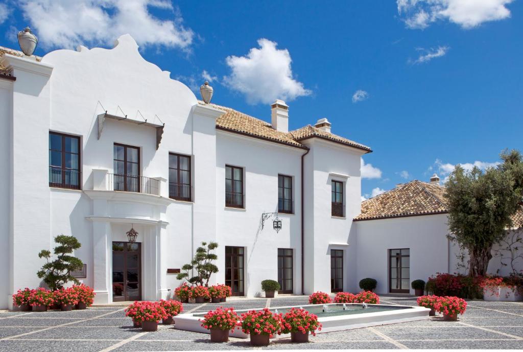 een wit gebouw met bloemen op een binnenplaats bij Finca Cortesin Hotel Golf & Spa in Casares