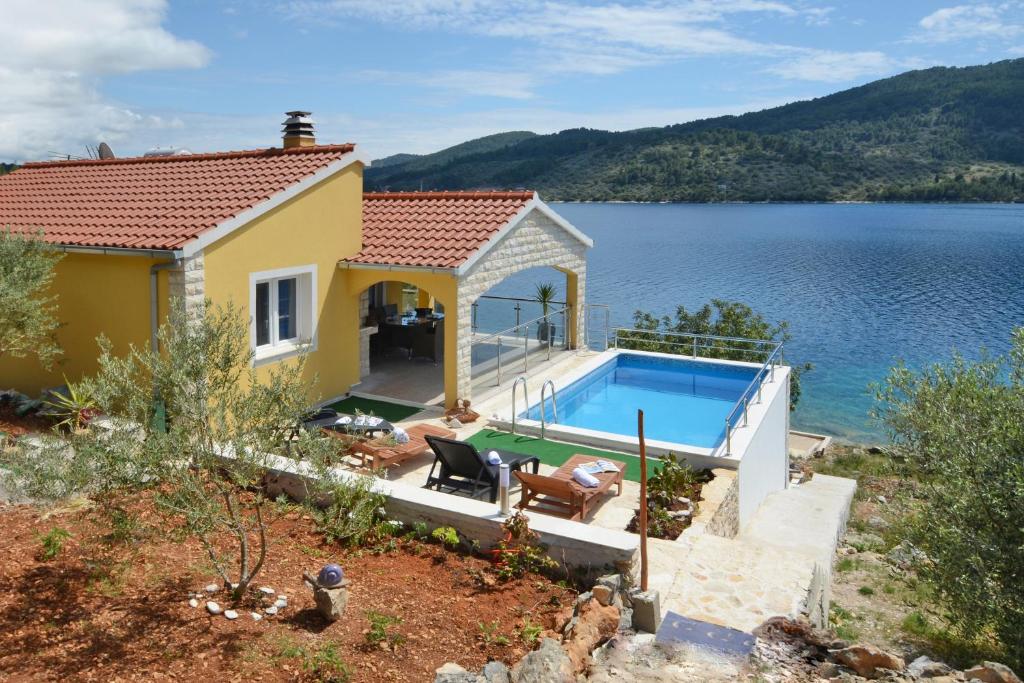 a house with a swimming pool next to a body of water at Villa Šeparović in Vela Luka