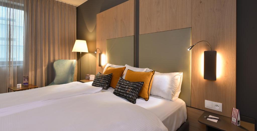 a hotel room with a large white bed with pillows at Martin's Louvain-la-Neuve in Louvain-la-Neuve