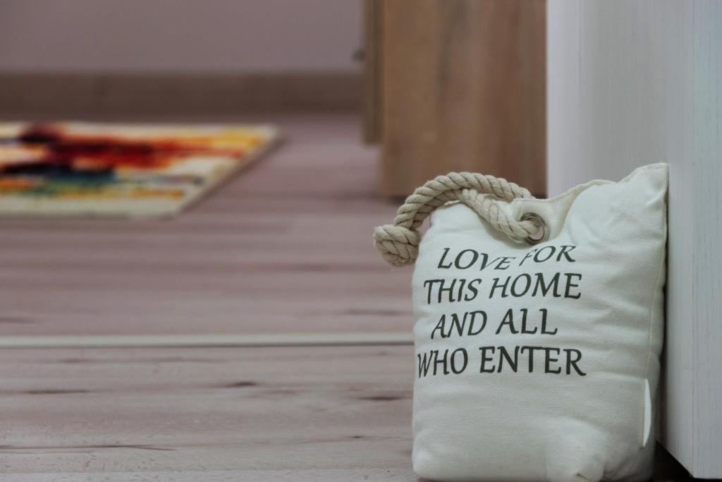 a pillow that says love for this home and all who enter at Bike-Friendly Apartment in Timişoara