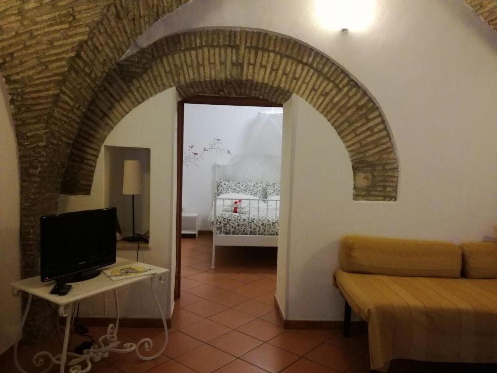 un arco en una habitación con sofá y 1 dormitorio en Svegliarsi nei Borghi - La Patronale, en Troia