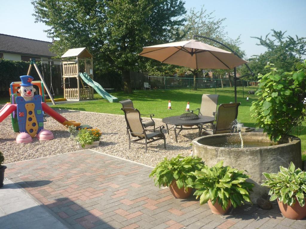 a park with a playground with a slide and an umbrella at Hoeve Mingels in Banholt