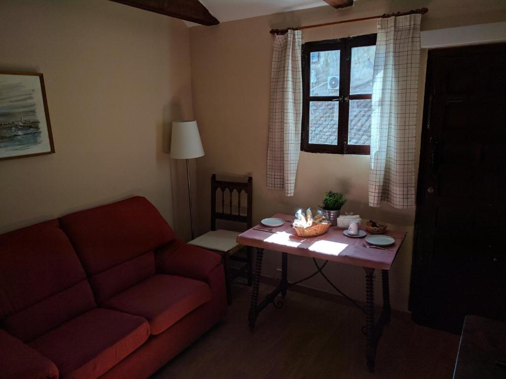 a living room with a red couch and a table at Acogedor apartamento en el casco histórico in Toledo