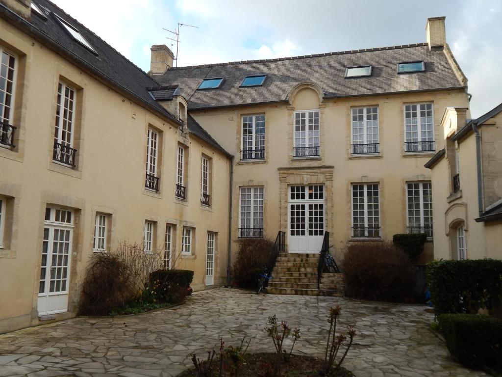 a large building with a cobblestone courtyard at Au cœur du centre historique in Bayeux