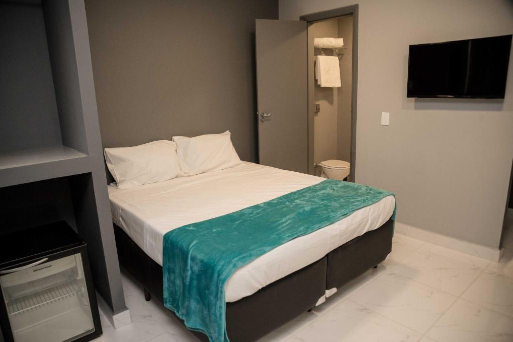 a bedroom with a bed with a blue blanket on it at REF House Barra Da Tijuca in Rio de Janeiro