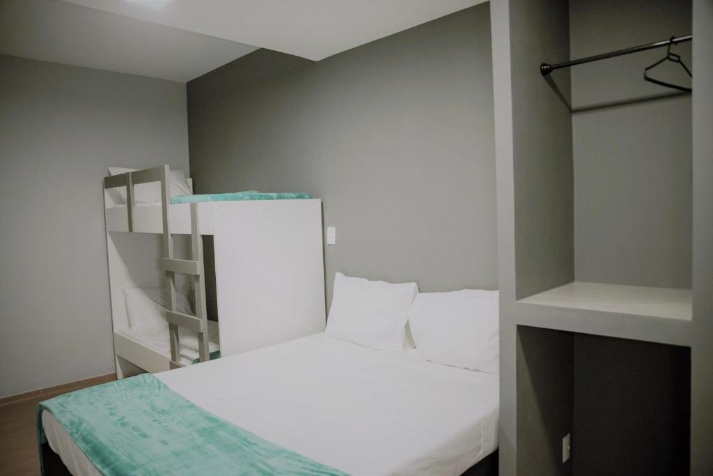 a small bedroom with a white bed and shelves at REF House Barra Da Tijuca in Rio de Janeiro