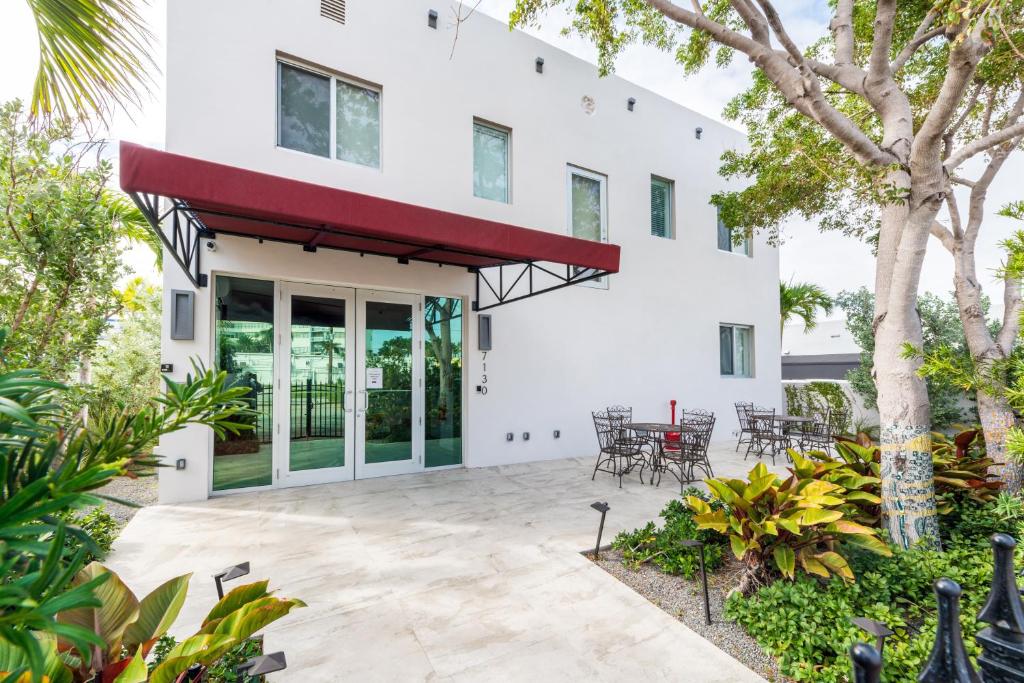 a white house with a patio with tables and chairs at Costa Norte Boutique Hotel in Miami Beach