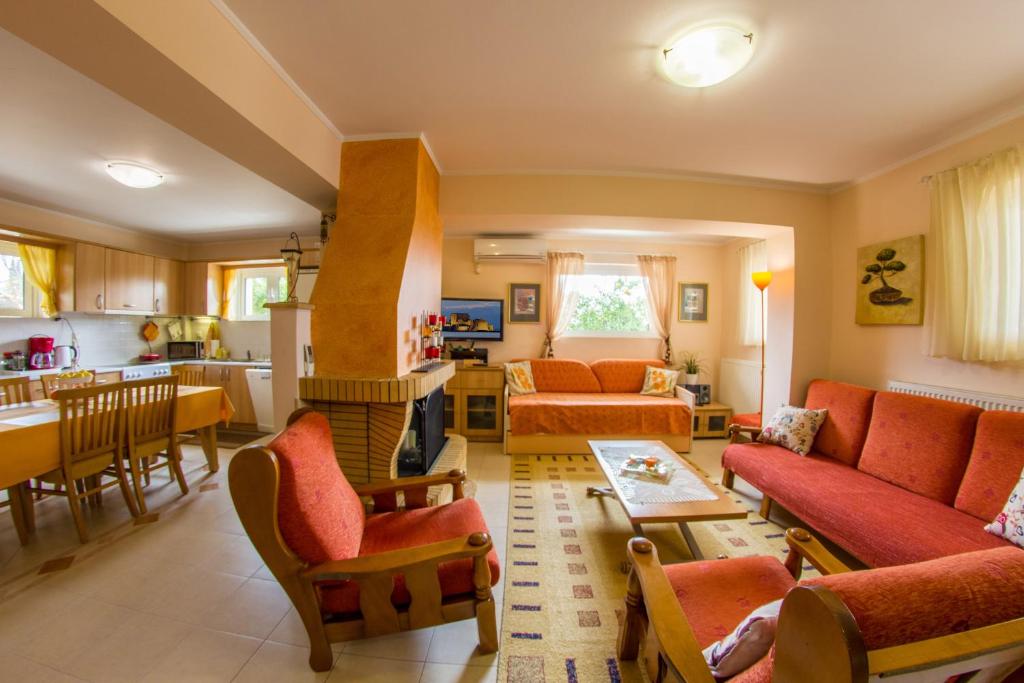 ナフプリオにあるIris-Gogo Houseのリビングルーム(オレンジ色のソファ付)、キッチンが備わります。