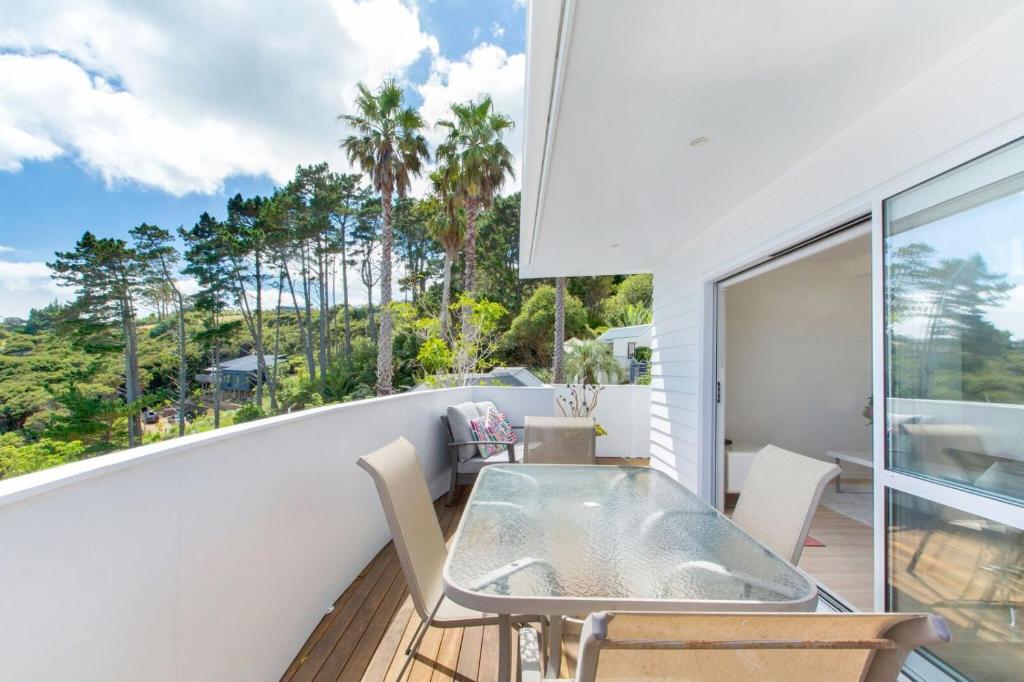 a patio with a table and chairs on a balcony at The Apartment at Palm Beach by Waiheke Unlimited in Palm Beach
