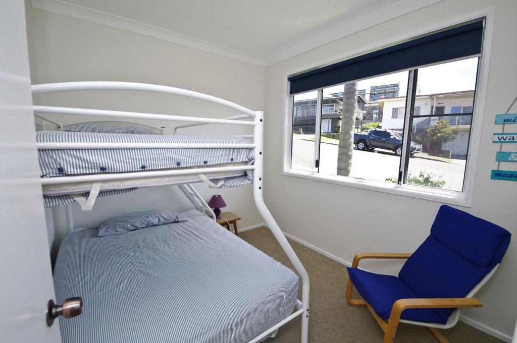 a bedroom with a bunk bed and a blue chair at Shiloh Holiday House, 14 East Street in Crescent Head
